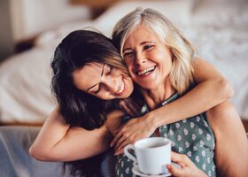 Liebevolle erwachsene Tochter umarmt fröhlich ihre Mutter