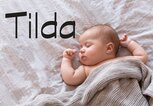 Baby liegt im Bett - dazu der Name Tilda | © iStock | Amax Photo