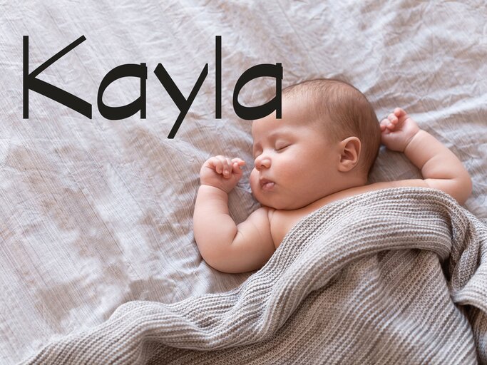 Baby liegt im Bett - dazu der Name Kayla | © iStock | Amax Photo