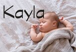 Baby liegt im Bett - dazu der Name Kayla | © iStock | Amax Photo