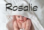 Baby liegt mit einem Handtuch eingewickelt im Bett - dazu der Babyname Rosalie | © iStock | SolStock
