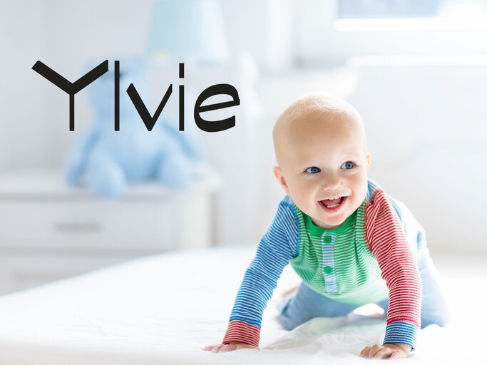 Glückliches Baby krabbelt im Bett - dazu der Name Ylvie | © iStock | FamVeld