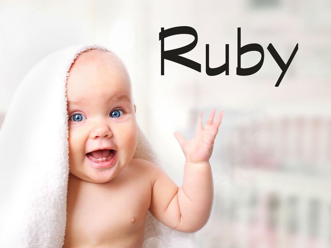 Süßes Baby mit Handtuch auf dem Kopf und daneben der Name Ruby | © iStock | NYS444