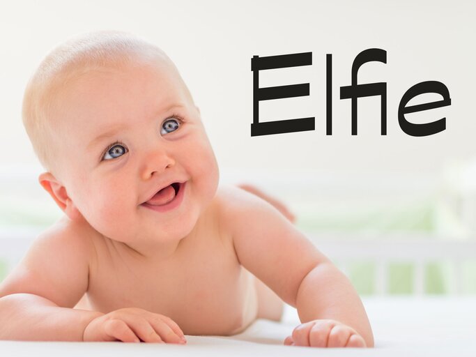 Glückliches Baby liegt im Bett - dazu der Name Elfie | © iStock | SanyaSM