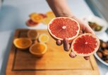 Frauenhand hält eine aufgeschnittene Grapefruit. | © iStock | ljubaphoto