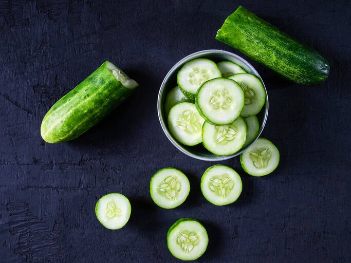 Frische aufgeschnittene Gurke auf einem dunklen Tisch. | © iStock | Narong KHUEANKAEW