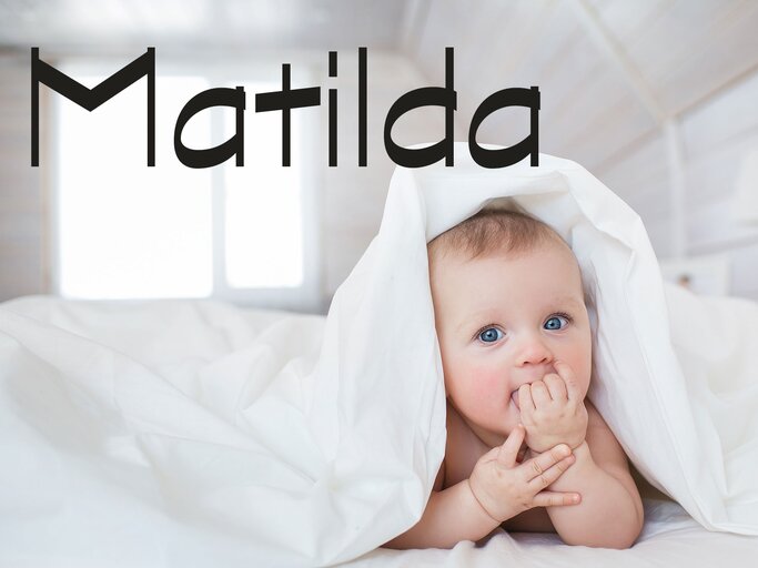 Süßes Baby mit Bettdecke auf dem Kopf und dem Namen Matilda | © iStock | KristinaKibler