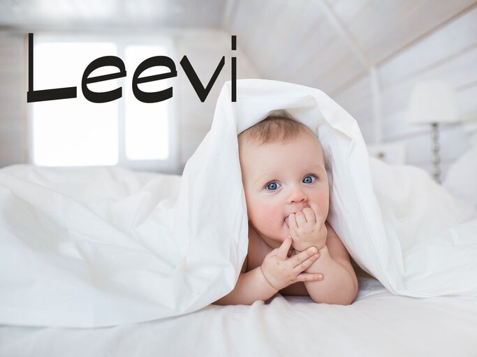 Süßes Baby in eine Bettdecke gekuschelt mit dem Namen Leevi | © iStock | KristinaKibler