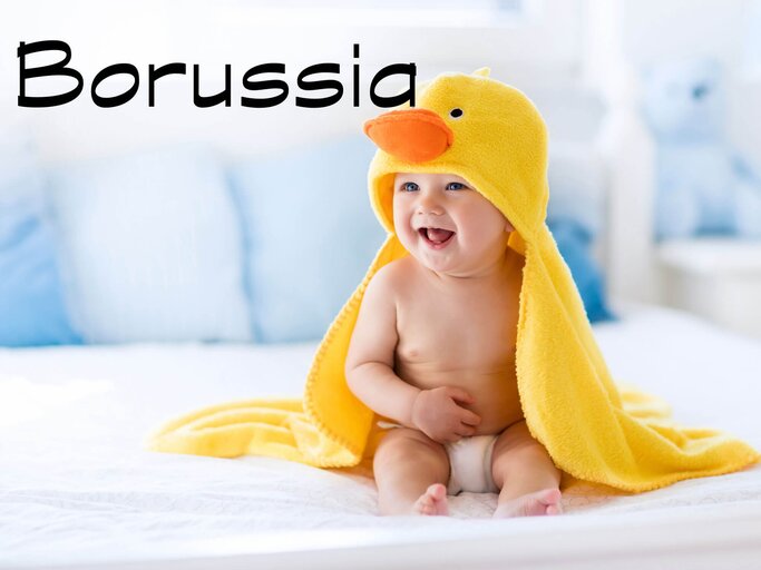 Baby sitzt auf dem Boden mit einem gelben Enten-Handtuch auf dem Kopf. | © iStock | FamVeld
