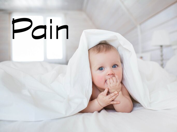 Baby liegt im Bett und schaut unter der Decke hervor.  | © iStock | KristinaKibler