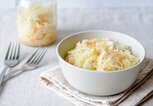 Nahaufnahme aus weißer Schale mit saftigem Sauerkraut auf Serviette mit Gabeln serviert | © iStock | serggn