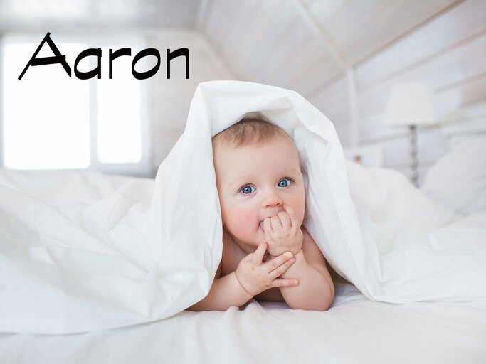 Süßes Baby mit Bettdecke auf dem Kopf und dem Namen Aaron | © iStock.com | KristinaKibler