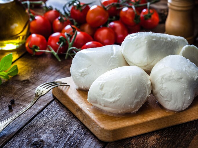 Mozzarella auf einem Brett mit Tomaten | © iStock.com | fcafotodigital