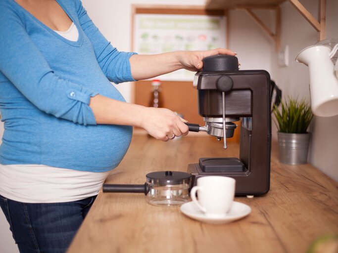Schwangere Frau bereitet einen Kaffee zu | © iStock.com | M_a_y_a