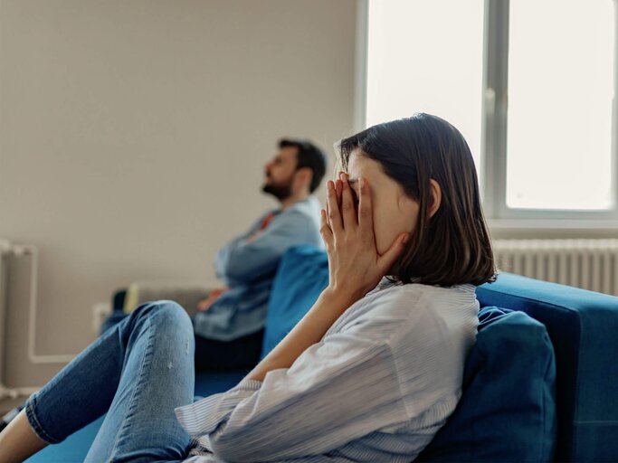 Paar sitzt auf der Couch und streitet sich. | © iStock.com / PixelsEffect