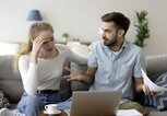 Paar diskutiert auf der Couch vor einem Laptop und Unterlagen.  | © iStock.com / fizkes