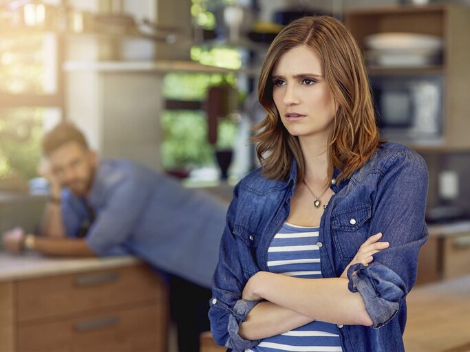 Eine Frau steht sauer in der Küche nach einem Streit mit ihrem Partner. | © iStock.com / PeopleImages