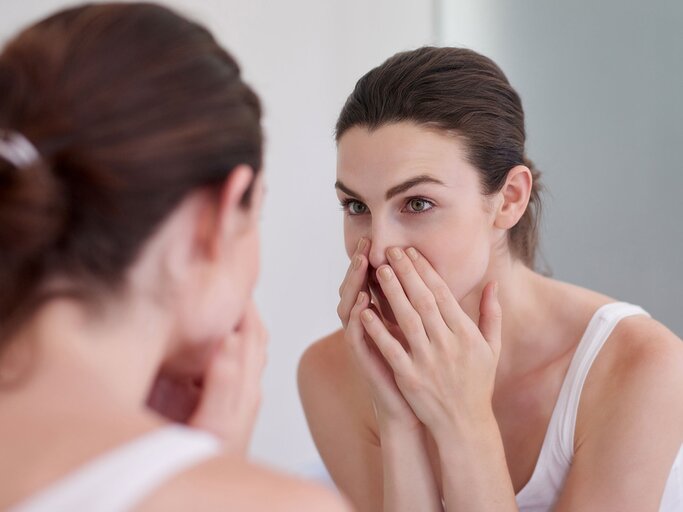 Frau untersucht ihre Haut auf Hauterkrankungen im Spiegel | © iStock.com / jeffbergen