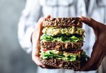 Frauenhände halten ein großes vegetarisches Sandwich mit Vollkorn | © iStock.com / alvarez