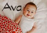Glückliches Baby liegt im Bett - dazu der Name Ava | © iStock | ozgurcankaya