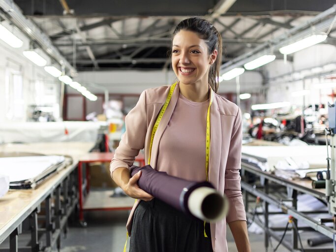 Lächelnde junge Frau in einer Mode-Fabrik | © iStock.com / Elitsa Deykova