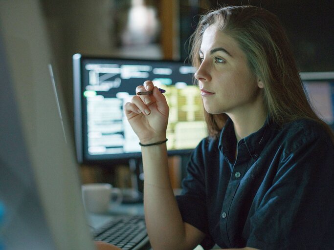 Frau überwacht konzentriert Monitore | © iStock.com / Laurence Dutton