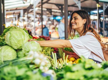 Junge Frau steht in der Gemüseabteilung und greift nach entzündungshemmenden Lebensmitteln. | © iStock | Obradovic