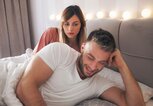 Paar liegt im Bett, er schaut auf sein Handy | © iStock.com / Jelena Danilovic