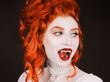 Frau mit roten Haaren geschminkt als Vampir an Halloween | © iStock.com / iiievgeniy