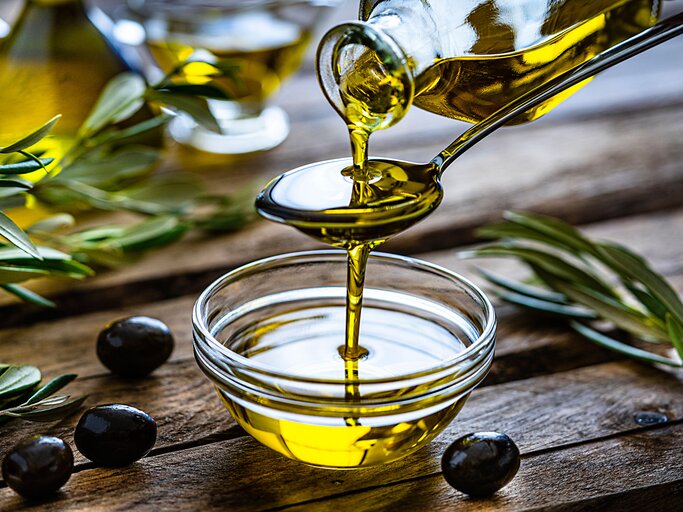 Gießen von nativem Olivenöl extra in eine Glasschüssel  | © iStock.com / fcafotodigital