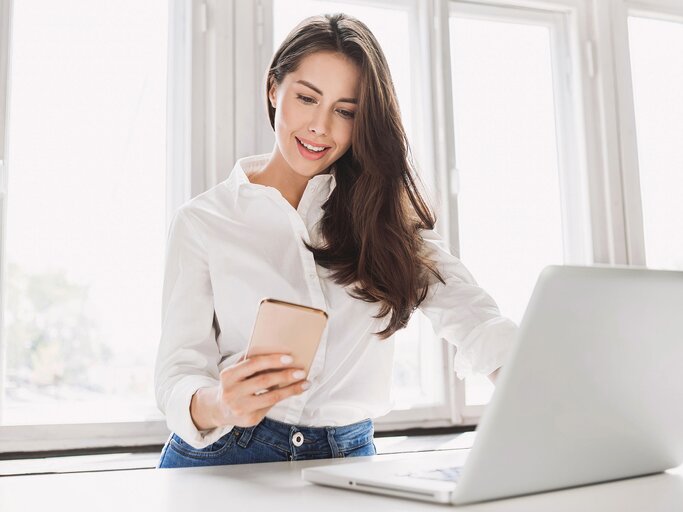 Schöne Geschäftsfrau mit Laptop und Smartphone  | © iStock.com / Poike