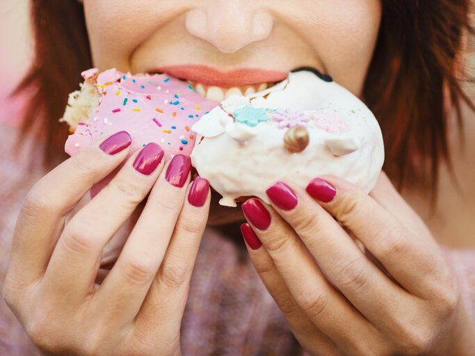 Frau beißt genüßlich in zwei Donuts | © iStock.com / Aja Koska