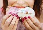 Frau beißt genüßlich in zwei Donuts | © iStock.com / Aja Koska