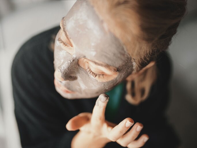 Frau trägt sich eine Heilerde-Maske im Gesicht auf | © iStock.com / Aja Koska