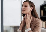 Frau hält aufgrund von Halsschmerzen ihren Hals. | © gettyimages.de / PeopleImages