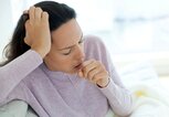 Frau sitzt mit einer Grippe auf der Couch und hustet. | © gettyimages.de / Science Photo Library