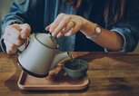 Frau schenkt sich am Tisch eine Tasse Grünen Tee ein. | © gettyimages.de / d3sign