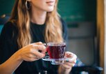 Eine Frau hält eine Tasse aus Glas in einer Hand, die roten Hagebutten-Tee enthält. | © gettyimages.de / agrobacter