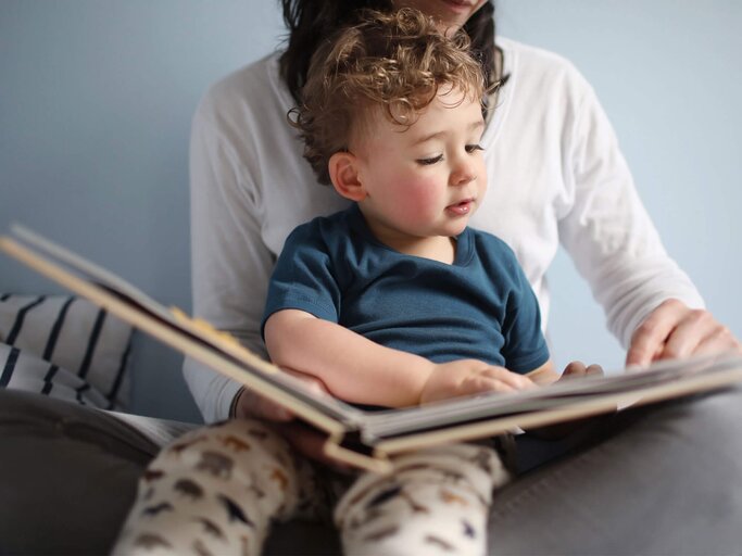 Eine Mutter liest mit ihrem Kind gemeinsam ein Buch. | © gettyimages.de / Catherine Delahaye