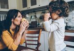 Eine Mutter und ihr Sohn trinken in der Küche aus Tassen. | © gettyimages.de / filadendron