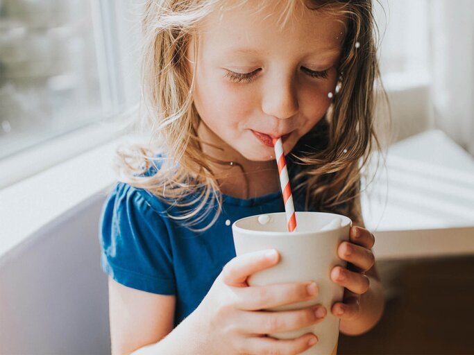 Ein Mädchen trinkt mit einem Papierstrohhalm ein Getränk aus einer Tasse. | © gettyimages.de / Catherine Falls Commercial