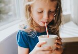 Ein Mädchen trinkt mit einem Papierstrohhalm ein Getränk aus einer Tasse. | © gettyimages.de / Catherine Falls Commercial