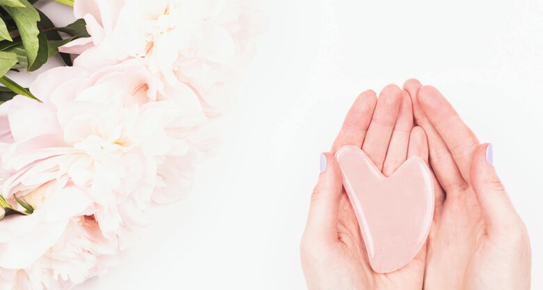 Frau hält Gua Sha Stein aus Rosenquarz in ihren Händen. | © gettyimages.de | Yulia Lisitsa