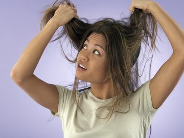 Frau fasst sich mit kritischem Blick in die Haare | © gettyimages.de | Fuse