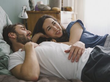 Paar liegt im Bett und unterhält sich | © Getty Images/	Halfdark