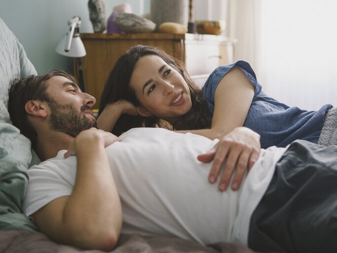 Paar liegt im Bett und unterhält sich | © Getty Images/	Halfdark