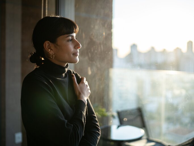 Frau blickt nachdenklich aus dem Fenster | © Getty Images/FG Trade