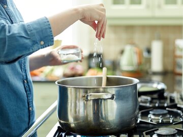 Frau salzt einen Topf mit kochendem Wasser | © Getty Images/	Neustockimages