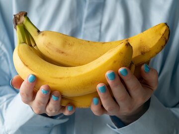 Frau hält in ihren Händen perfekt gereifte Bananen | © Getty Images/	Aleksandr Zubkov