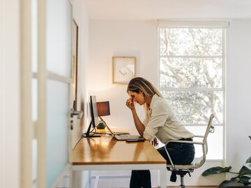 Frau sitzt unglücklich am Schreibtisch | © Getty Images/	jacoblund